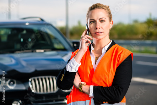 Woman with car breakdown calling towing company with phone