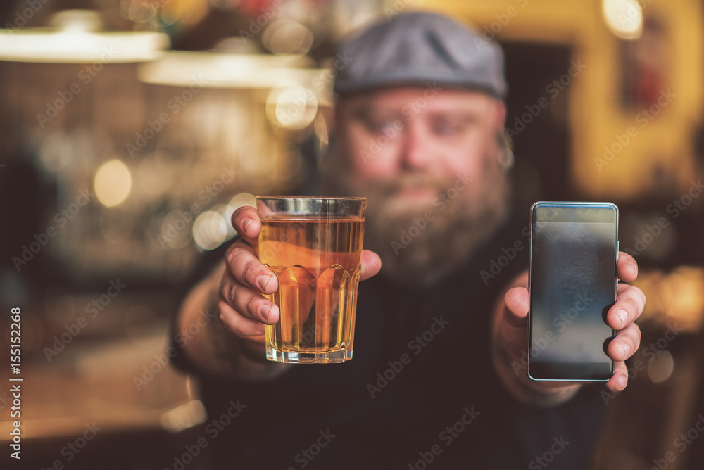 Man showing off a drink and his cell phone