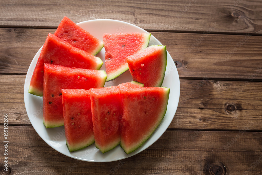 Juicy watermelon on a plate on the wooden background.
Juicy watermelon on a plate on the wooden background.