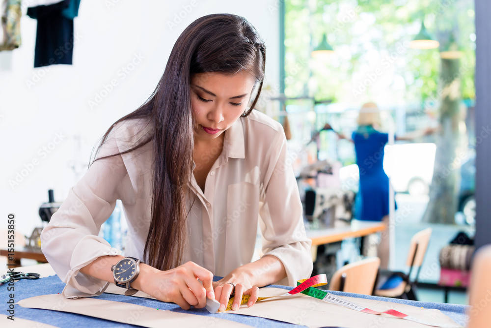 Asian fashion designer woman drafts cut pattern in her workshop Asian fashion designer woman drafts cut pattern in her workshop