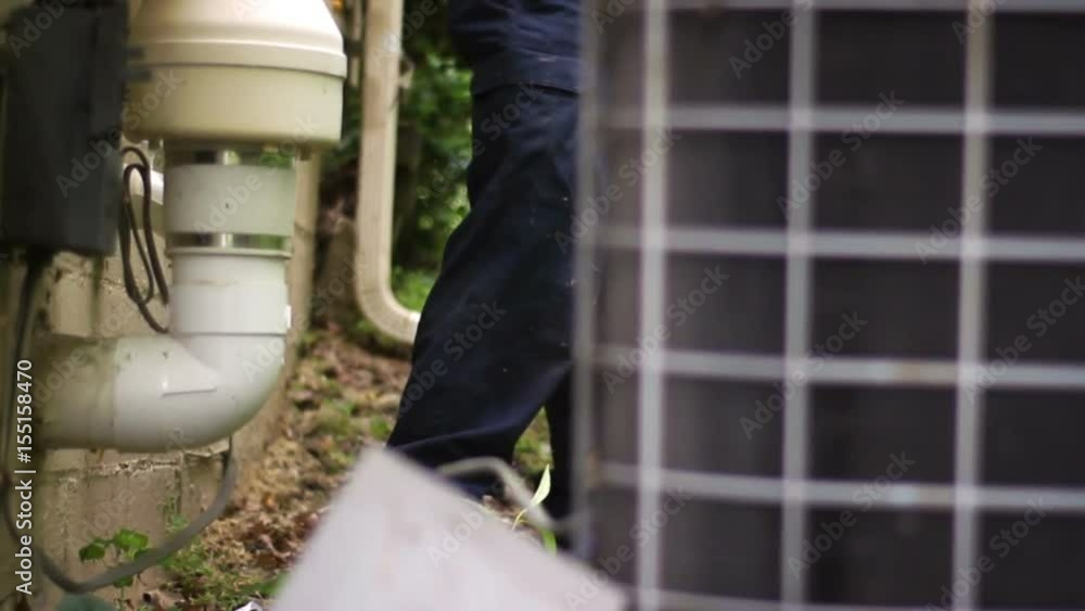 HVAC technician removing cables between air conditioner and house exterior HVAC technician removing cables between air conditioner and house exterior