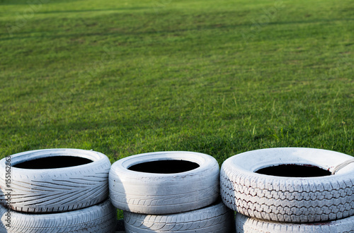 Painted white old tires on kart race course over green grass background photo