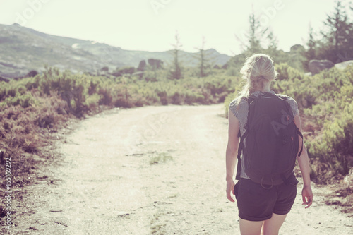 Active sporting beautiful woman, Young european woman on day trip in summer countryside, Active women in countryside, Blonde girl in barren landscape, Tourist with backpack on walk © marvlc