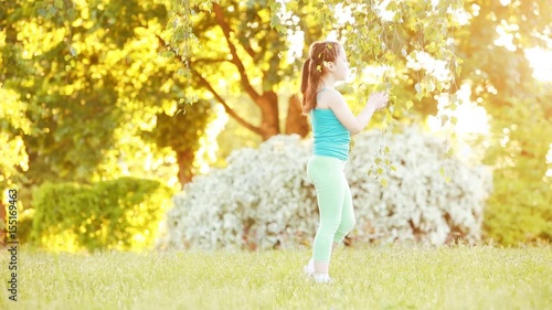Cute little girl walking under tree in the park at sunshine summer day.