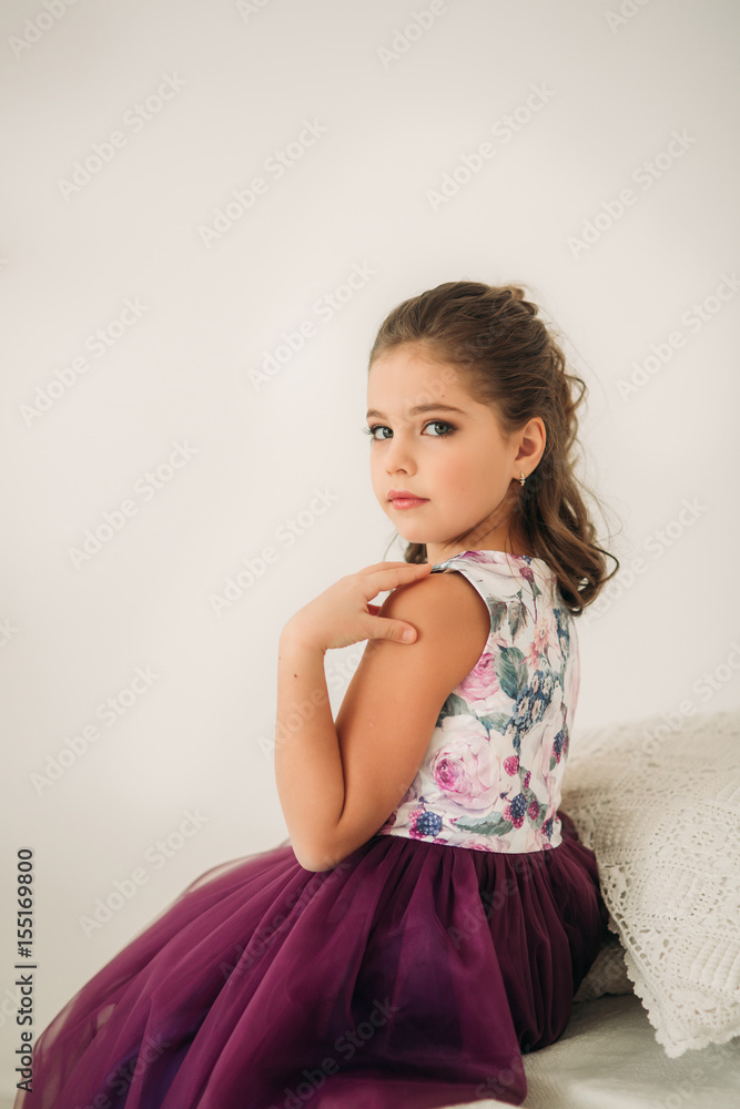 Beautiful girl in a purple dress and flower blouse posing for a photographer. Beautiful girl in a purple dress and flower blouse posing for a photographer.