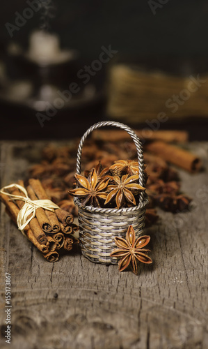 Food background with Close-up Star Anise placed in tiny metal basket with fresh cinnamon sticks on rustic wooden table