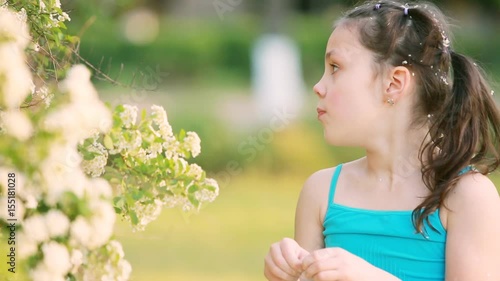 Close-up of little girl enjoys the smell of flowers in the meadow in summer.
