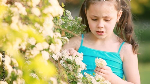 Close-up of little girl enjoys the smell of flowers in the meadow in summer.