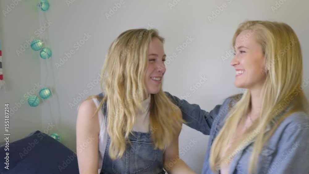 Girl Plays On Her Phone, Her Friend Hops On Her Bed And They Hug And Chat Girl Plays On Her Phone, Her Friend Hops On Her Bed And They Hug And Chat