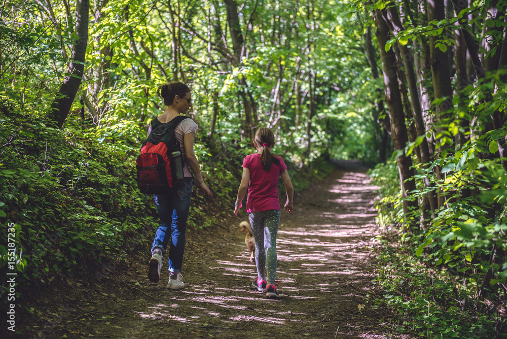 Obraz premium Mother and daughter walking on path in woods