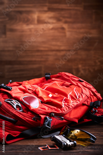 Weather backpack, sunglasses and gear for the bicycle on the wooden background.