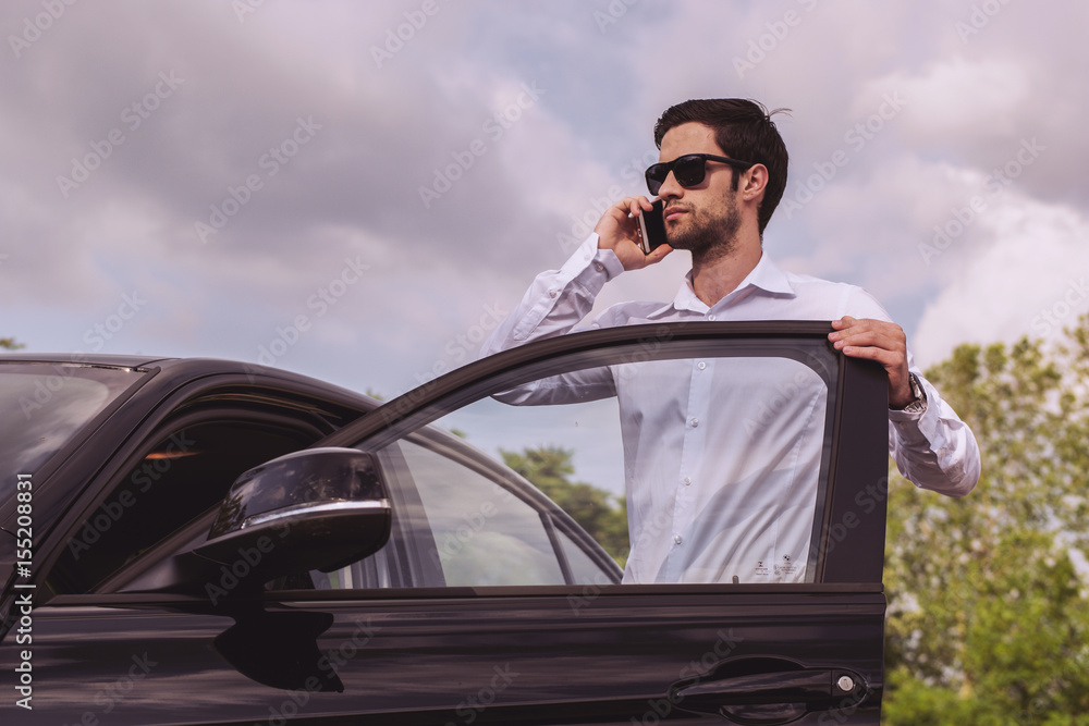 Young guy beside broke car speaking on phone Young guy beside broke car speaking on phone