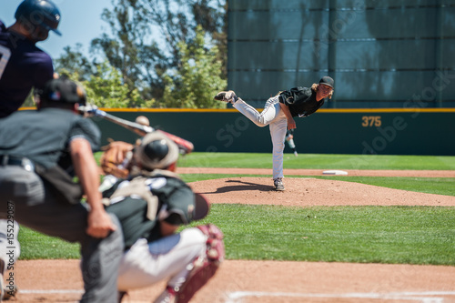 Baseball pitcher following through to pitch to right handed batter.  photo