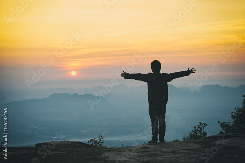 A man standing on the rock in the morning with sunrise and mountain.