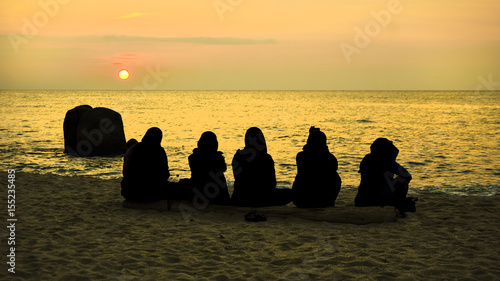 Sunrise silhouette of 5 young women at beach