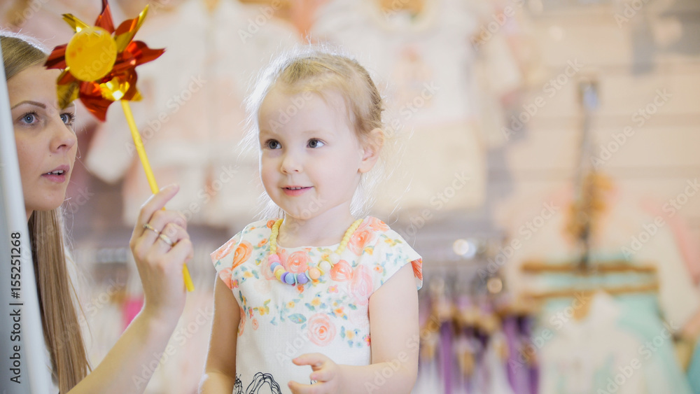 The girl and her mother playing in the store in front of the mirror in the children's clothing store The girl and her mother playing in the store in front of the mirror in the children's clothing store