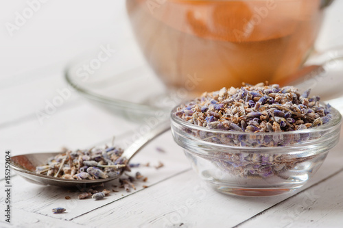 a cup of tea with fresh and dried lavender flowers on a white background. Natural herbal tea in a white porcelain cup garnished with fresh and dried herbs. Photo from above.