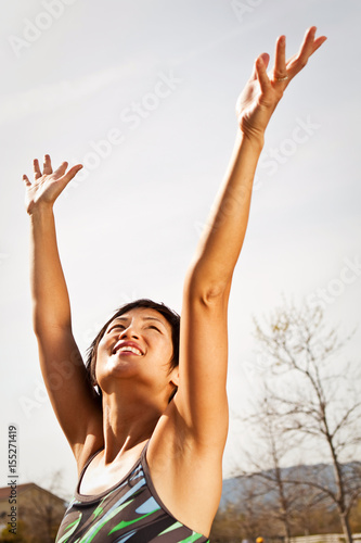 Heathly Asian woman exicited with hands in the air.
