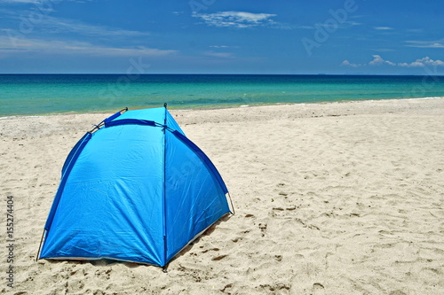 sun tent  on white sand beach  in front of  turqouise water in a sunny day with white clound and blue sky. © keng666