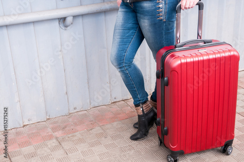 Woman in jeans with a red suitcase