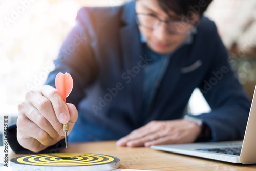 Canvas Print Business Man hand holding a target with darts hitting the center