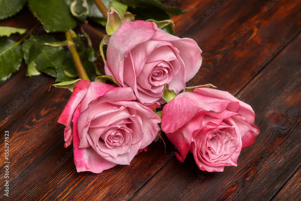 Three beautiful pink roses on wooden table, romantic background Three beautiful pink roses on wooden table, romantic background