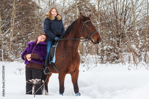 Teenager girl, mom and horse in a winter