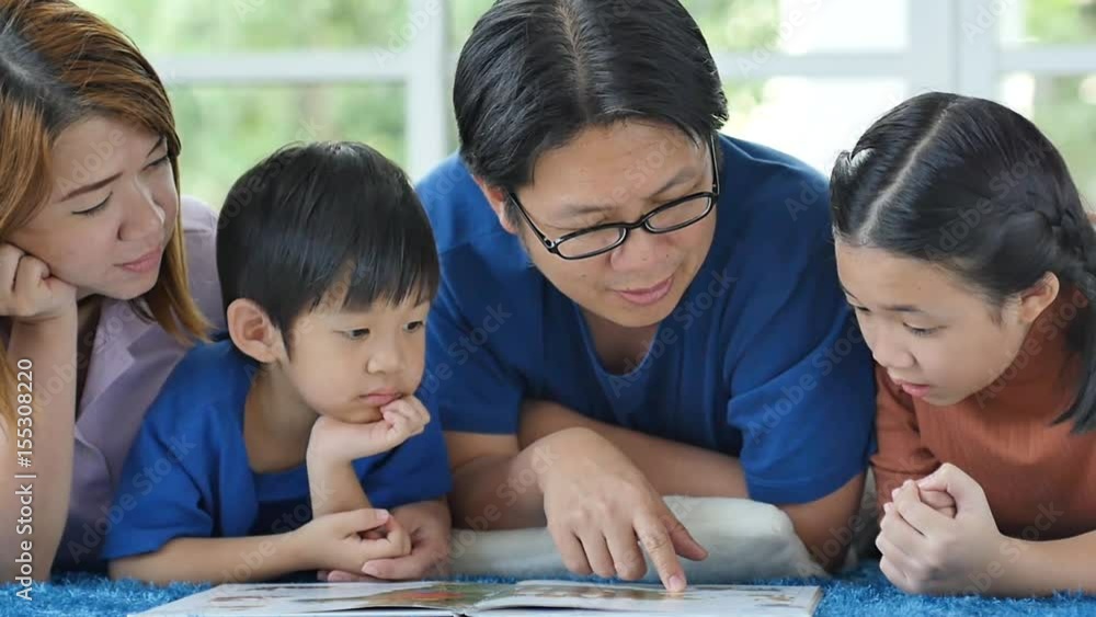 Happy Asian family reading book at home Happy Asian family reading book at home