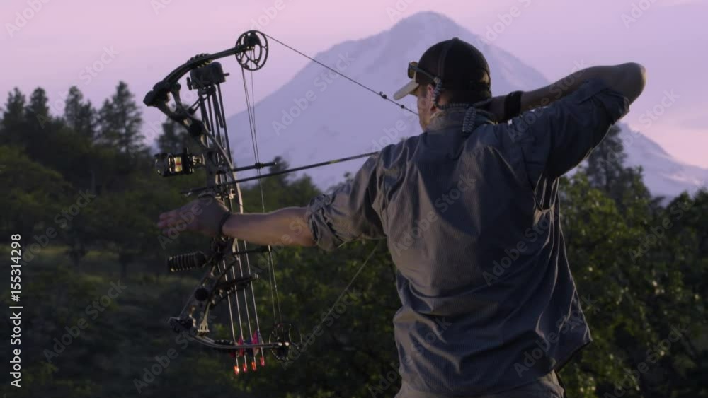Elk Hunter Practices Using His Compound Bow At Sunset In The Mountains Elk Hunter Practices Using His Compound Bow At Sunset In The Mountains