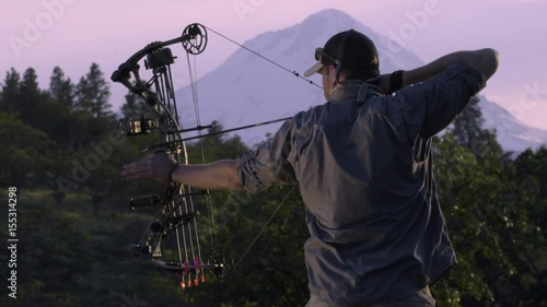 Elk Hunter Practices Using His Compound Bow At Sunset In The Mountains