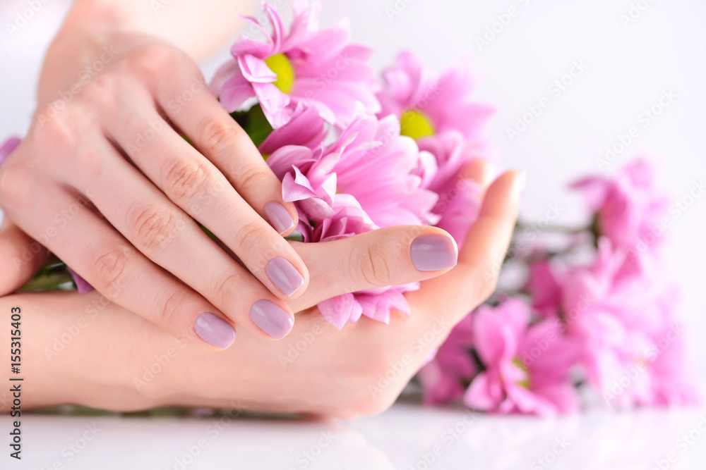 Hands of a woman with pink manicure on nails and pink flowers Hands of a woman with pink manicure on nails and pink flowers