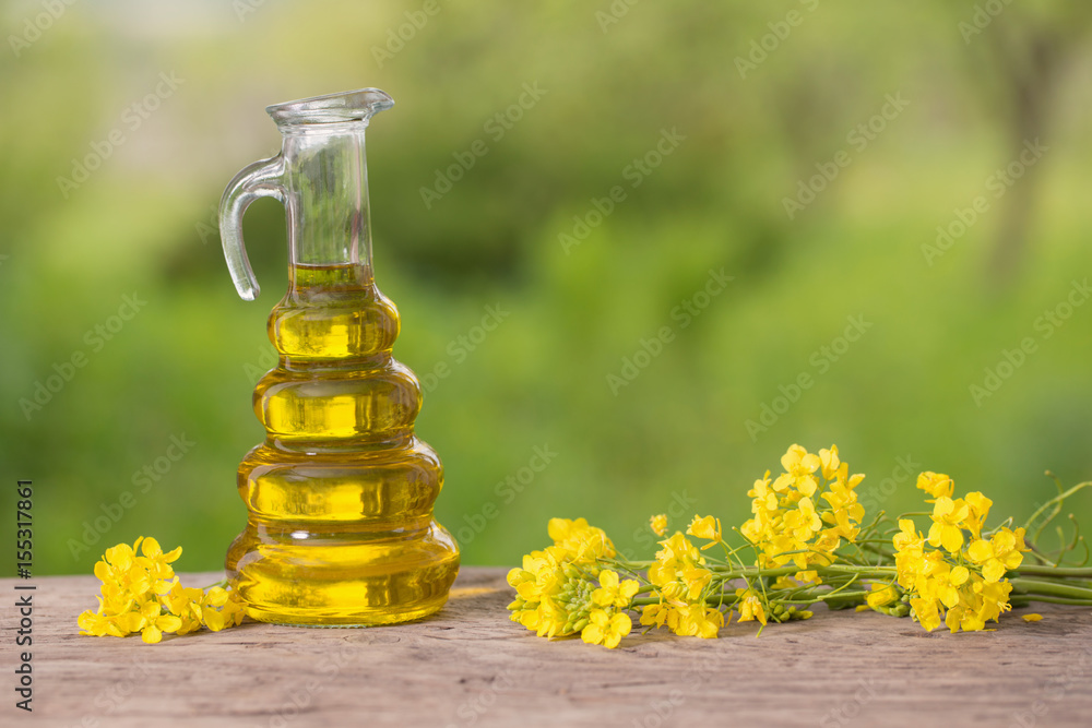 rapeseed oil (canola) and rape flowers on wooden table rapeseed oil (canola) and rape flowers on wooden table