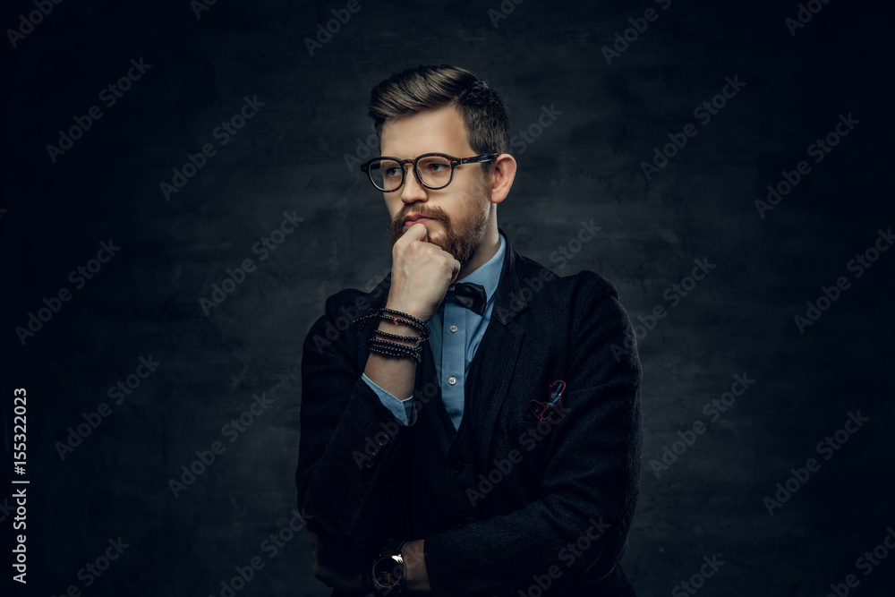 Bearded elegant male in eyeglasses dressed in a dark blue suit with bow tie. Bearded elegant male in eyeglasses dressed in a dark blue suit with bow tie.