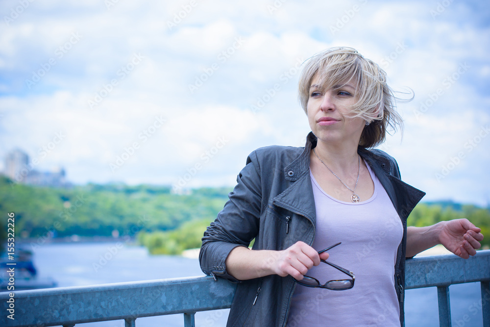 Fototapeta premium Blond head american woman rest after work in city. Citizen girl relax around river and park