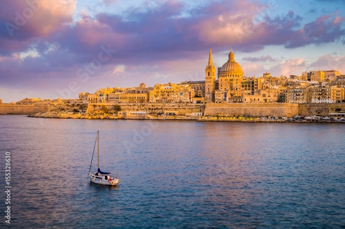 Valletta, Malta - St.Paul's Cathedral in golden hour at Malta's capital city Valletta with sailboat and beautiful colorful sky and clouds