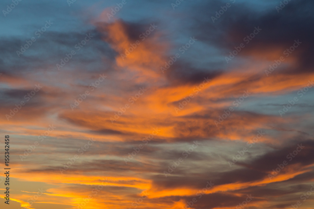 sunset in dramatic blue sky with clouds in orange color tones