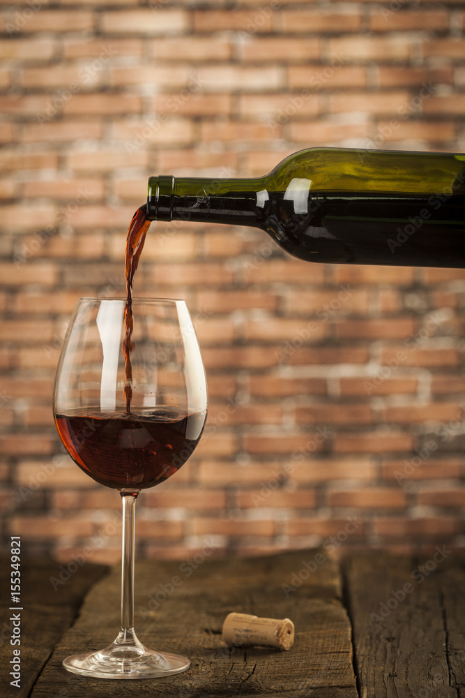 Wine glass and bottle on a wooden table with bricks wall background