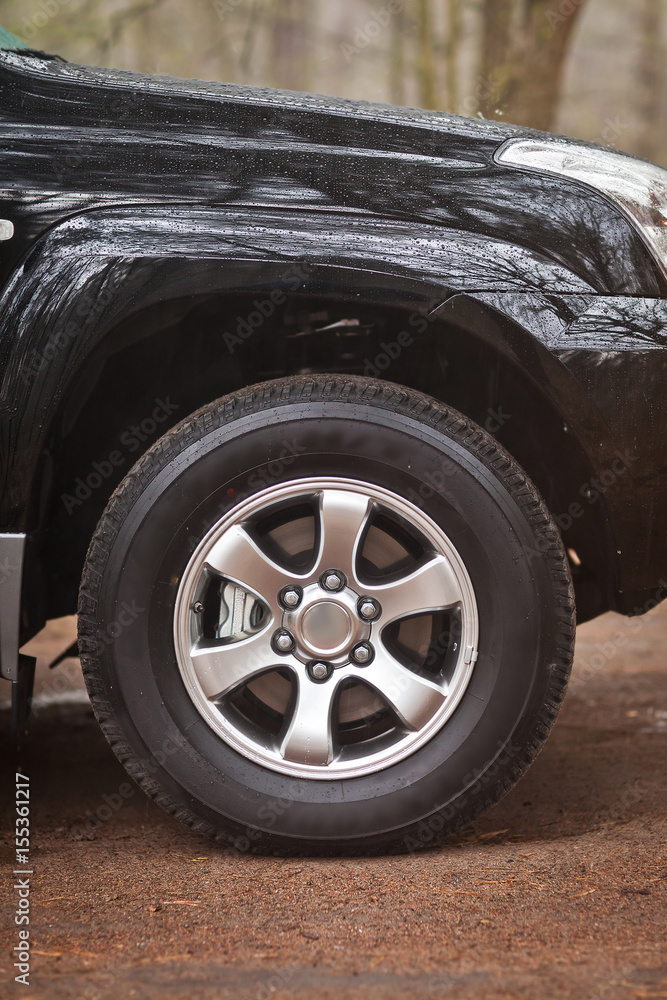 Close-up photo wheel of an SUV that stands in the woods