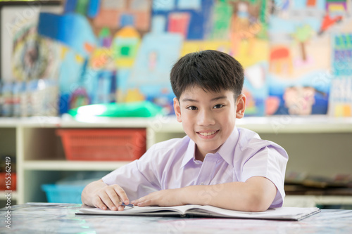 Happy asian child reading book with smile face.