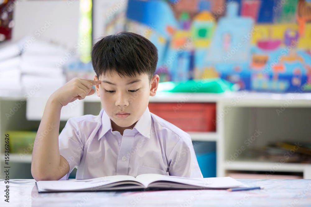 Happy asian child reaHappy asian child reading book and thinking about that .ding book with smile face. Happy asian child reaHappy asian child reading book and thinking about that .ding book with smile face.