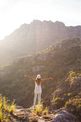 Girl raising arms infront of mountain range