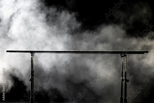 Closeup. Gymnastic parallel bars. Isolated on black background with fog,