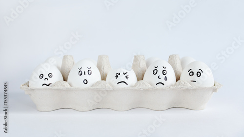 Eggs with funny faces in the package on a white background. Easter Concept Photo. Faces on the eggs