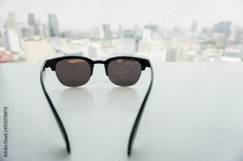 isolated modern design men sunglasses on white table with city backdrop