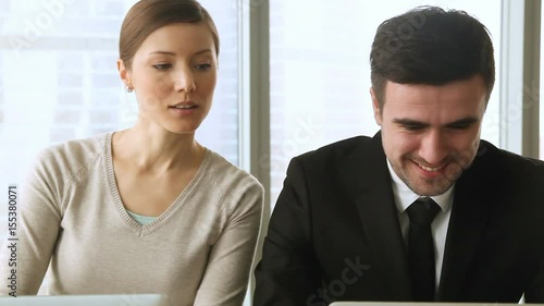 Young nosy female spying co-worker taking inquisitive glance, sneaking peek at laptop screen of male colleague, intruding on privacy, stealing ideas, private information from computer of competitor