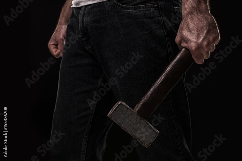 Male offender with a big hammer. On black background at the studio