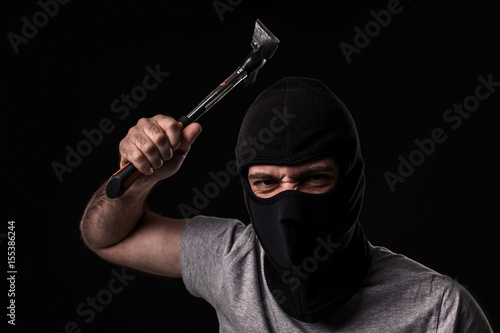 Criminal in T-shirt and balaclava with hammer