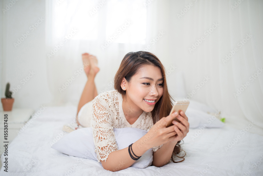 Woman Relaxing in bed and using mobile phone, relaxing in her living room Woman Relaxing in bed and using mobile phone, relaxing in her living room
