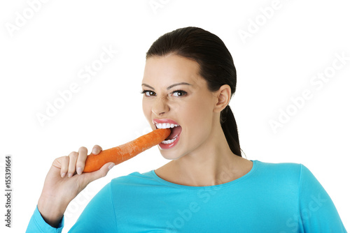 Beautiful girl bites carrots on white