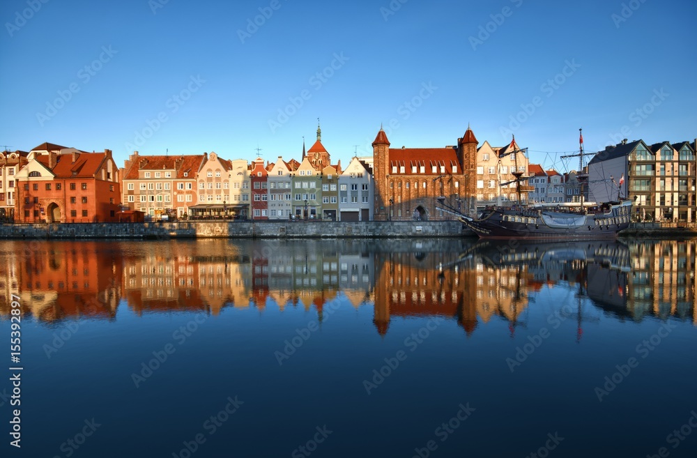Caravel moored by Long Embankment on Motlawa River in the Old Town of Gdansk, Poland at sunrise. Straganiarska Gate in the center